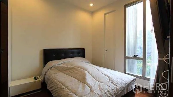 Condominium for rent - Bedroom with double bed, window and city outlook over Bangkok.