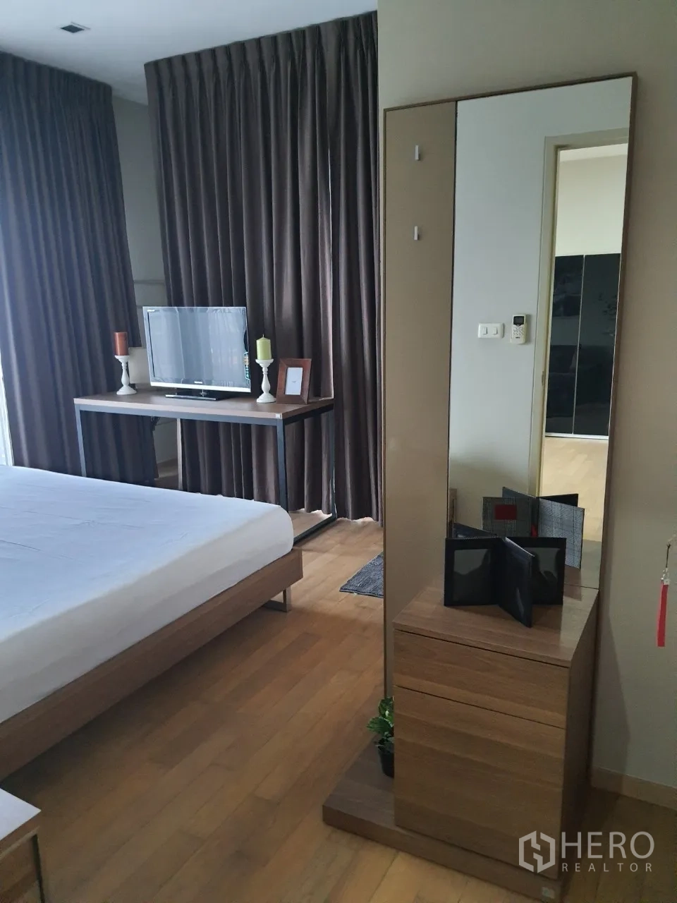 Condominium for rent or sale in Watthana, Bangkok - Bedroom area with dressing table and full-height mirror beside large windows and curtains.