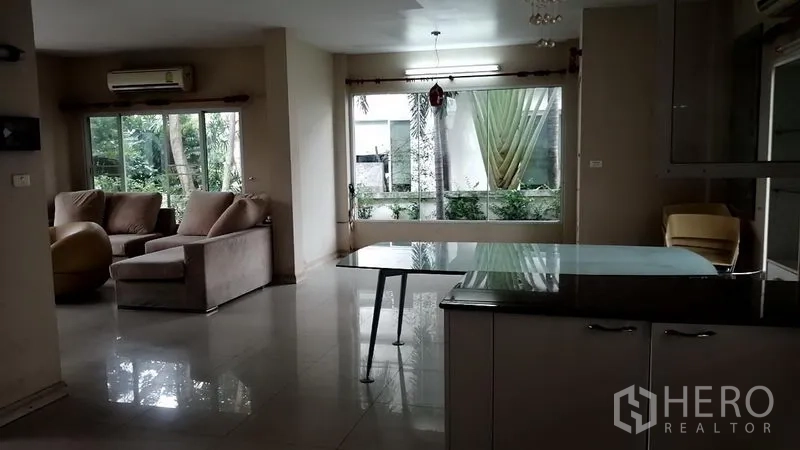 บ้าน ให้เช่าในLat Krabang, Bangkok - โถงรับแขก–ทานอาหารมองเห็นสวนผ่านหน้าต่างบานกว้างและประตูกระจก