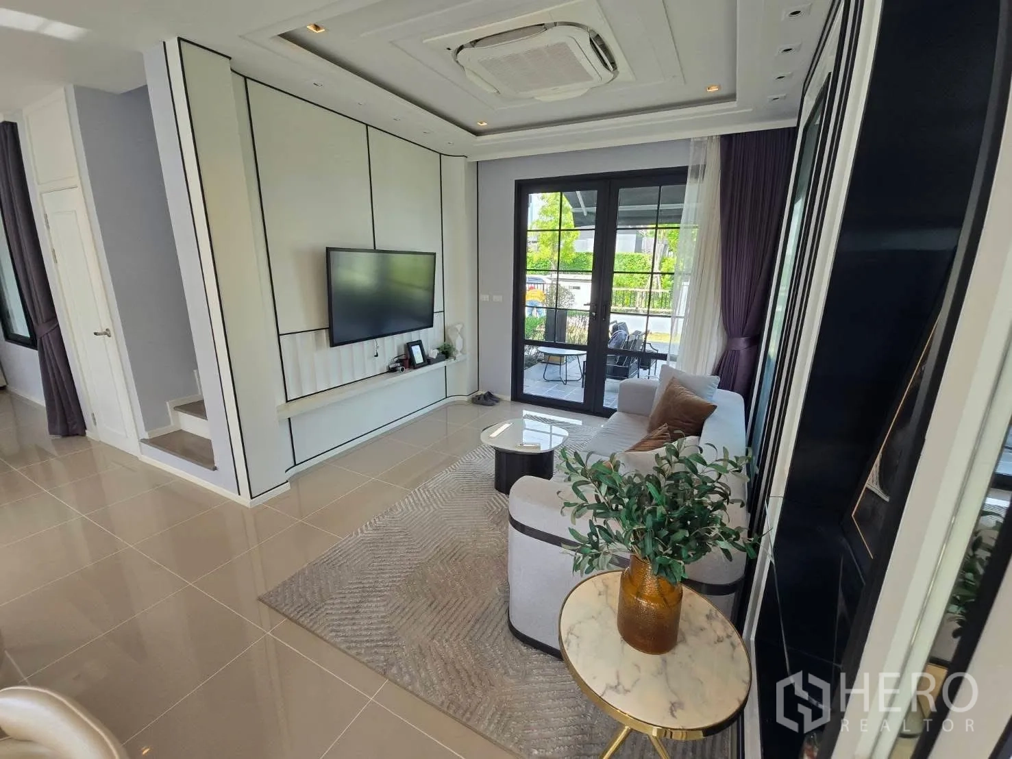 Semi-detached House for rent in Bang Phli, Samut Prakan - Living area view to terrace with sofa, rug, and feature TV wall.