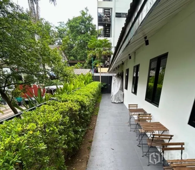 零售空间 出租在Yan Nawa, Bangkok - 建筑侧边露台步道，绿篱与户外座椅。