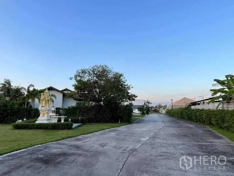 คลังสินค้า ขายในChon Buri - ถนนคอนกรีตภายในโครงการ มีแนวรั้วพุ่มไม้และศาลพระภูมิแต่งสวน