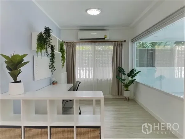 บ้าน ให้เช่าในSuan Luang, Bangkok - มุมทำงานรับแสงธรรมชาติ มีโต๊ะ ชั้นวาง แอร์ และต้นไม้กระถางข้างหน้าต่างบานกว้าง.