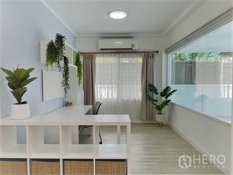 บ้าน ให้เช่าในSuan Luang, Bangkok - มุมทำงานรับแสงธรรมชาติ มีโต๊ะ ชั้นวาง แอร์ และต้นไม้กระถางข้างหน้าต่างบานกว้าง.