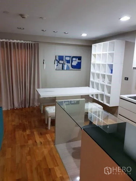 Condominium for sale in Bang Rak, Bangkok - Dining nook with white table, pendant lights and cube shelving unit.