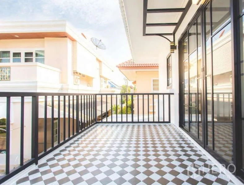 Detached House for sale in Wang Thonglang, Bangkok - Upper balcony with checkerboard floor tiles and black railing beside large sliding doors.