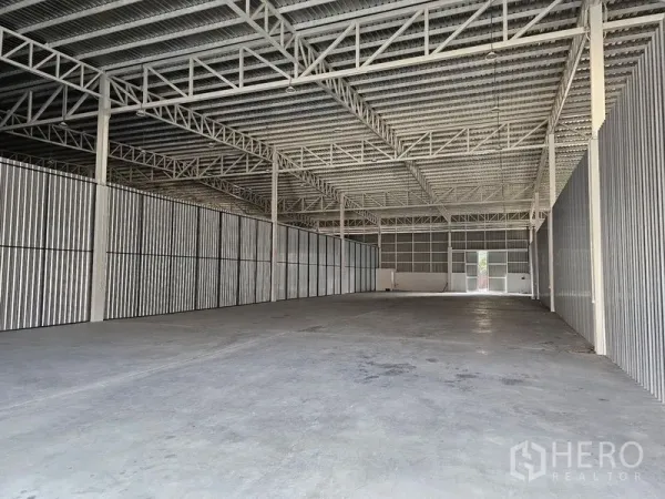 货栈 出租在Khlong Toei, Bangkok - 空旷的仓库内部，高钢桁架屋顶与耐用混凝土地面。