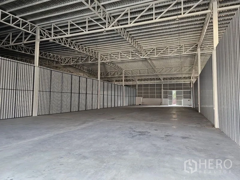 货栈 出租在Khlong Toei, Bangkok - 空旷的仓库内部，高钢桁架屋顶与耐用混凝土地面。