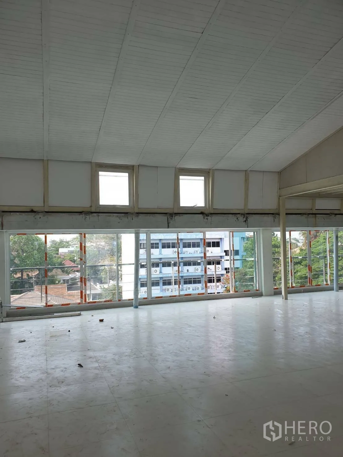 Office Space for rent or sale - Open-plan floor with high insulated ceiling and full-height windows over the neighborhood.