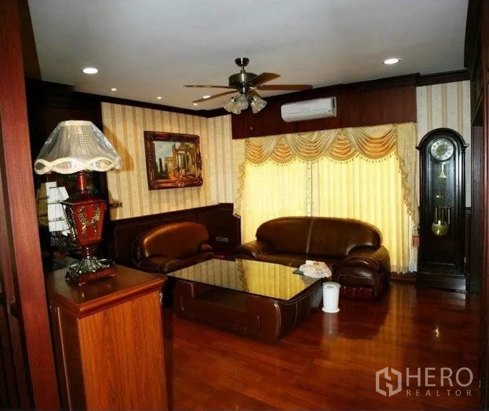 Detached House for sale in Phra Samut Chedi, Samut Prakan - Warm lounge with leather sofas, wood wall panels, ceiling fan and a grandfather clock.