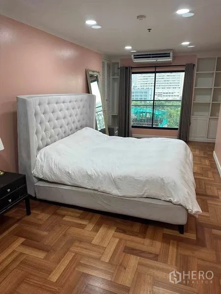公寓 出售在Bangkok - 主卧配大窗、内置层架、空调与城市景观。