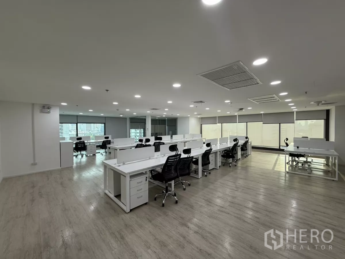 办公空间 出租在Din Daeng, Bangkok - 采光充足的开放式办公区，成排白色工位与黑色人体工学椅，配大窗与卷帘。