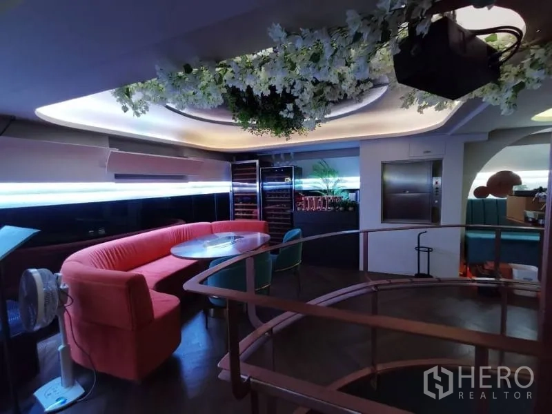 พื้นที่ขายปลีก ให้เช่า - มุมชั้นลอยพร้อมโซฟาโค้ง โต๊ะกลม ตู้ไวน์ และดอกไม้แขวน