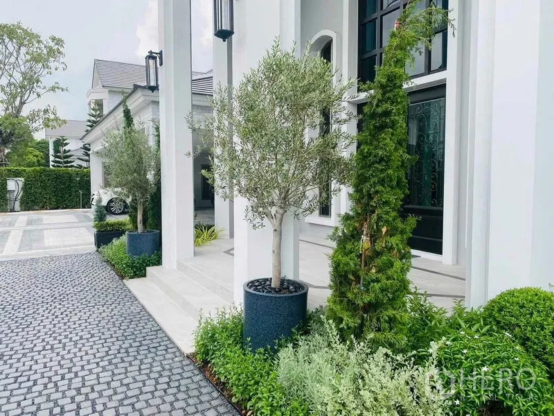 บ้าน ขายในLat Krabang, Bangkok - ทางเข้าหน้าบ้านเสาใหญ่ พร้อมต้นไม้กระถางและพรรณไม้ตัดแต่ง