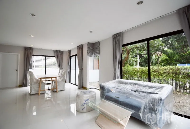 Detached House for rent in Prawet, Bangkok - Bright open-plan living and dining room with floor-to-ceiling windows and garden outlook.