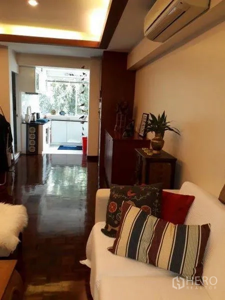 คอนโด ให้เช่าในPathum Wan, Bangkok - พื้นที่นั่งเล่นแบบเปิดพร้อมโซฟาและพื้นไม้ เชื่อมต่อไปยังครัวหน้าต่างกว้างวิวต้นไม้