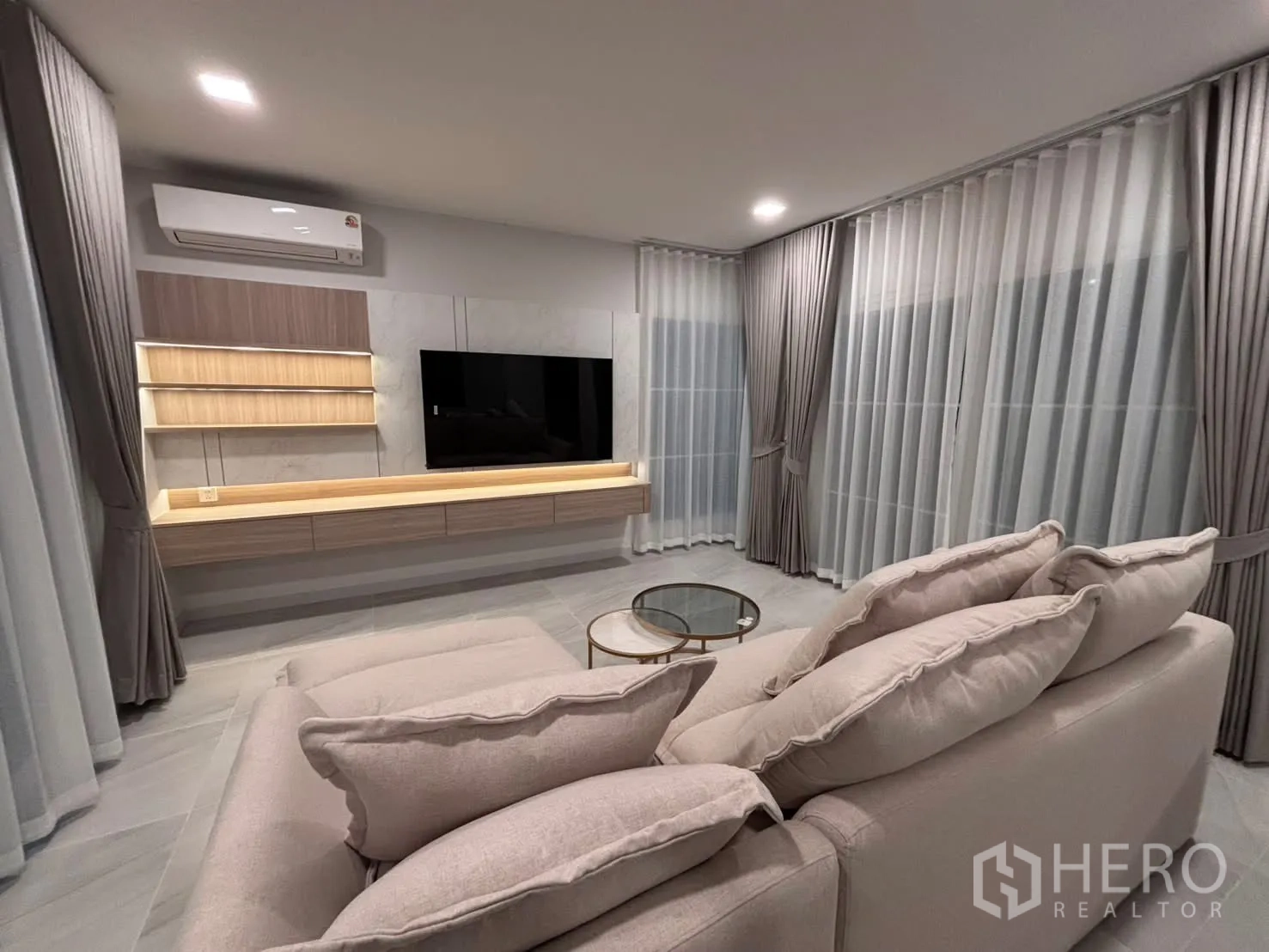 独栋房屋 for rent in Bang Phli, Samut Prakan - 客厅配转角沙发、电视柜与落地窗帘。
