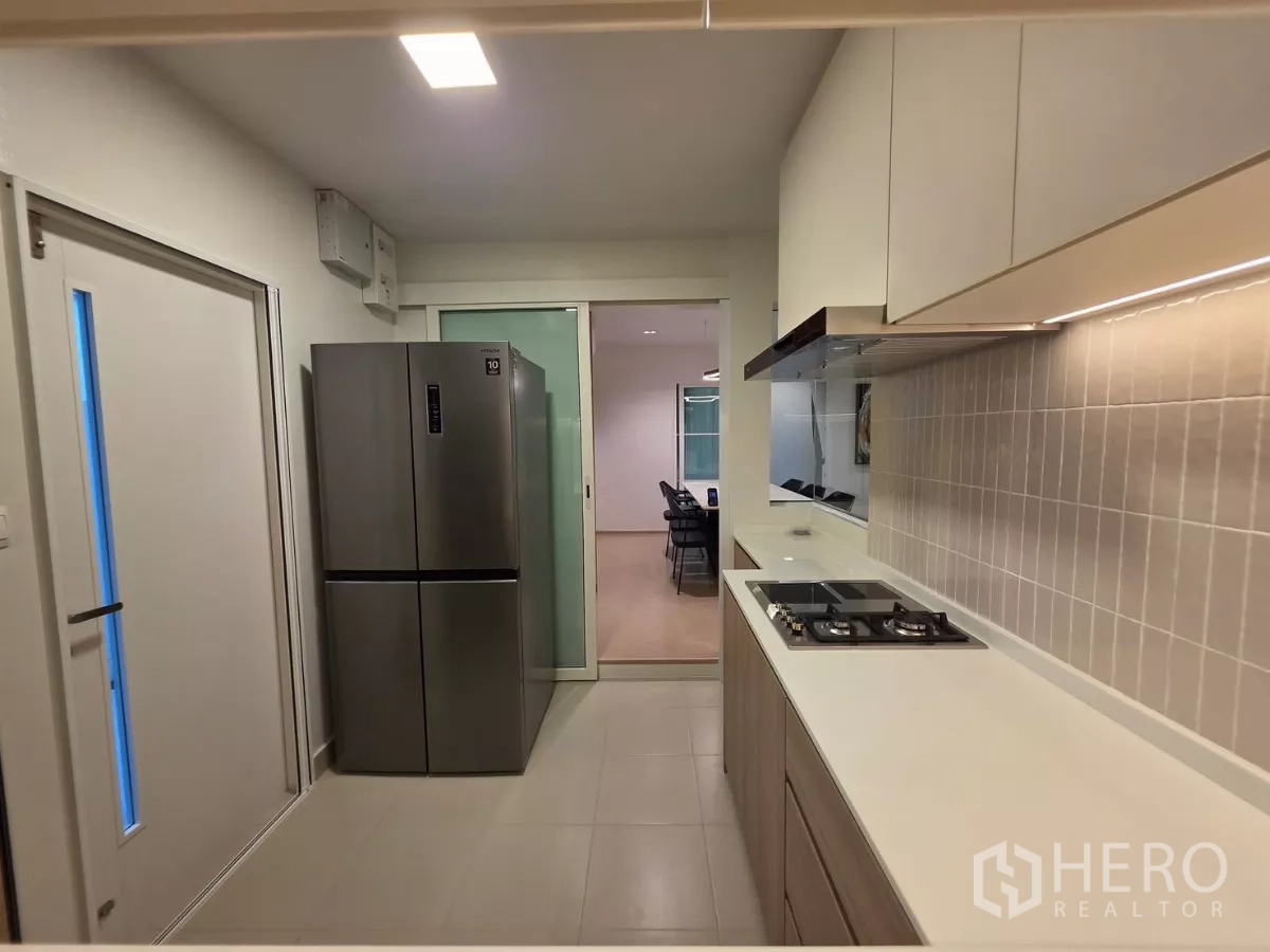 Detached House for rent in Bang Phli, Samut Prakan - Kitchen corridor with long countertop, range hood and double-door refrigerator.