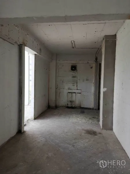 零售空间 出租在Watthana, Bangkok - 零售单元的走廊式毛坯内部，裸露墙面与基础照明。