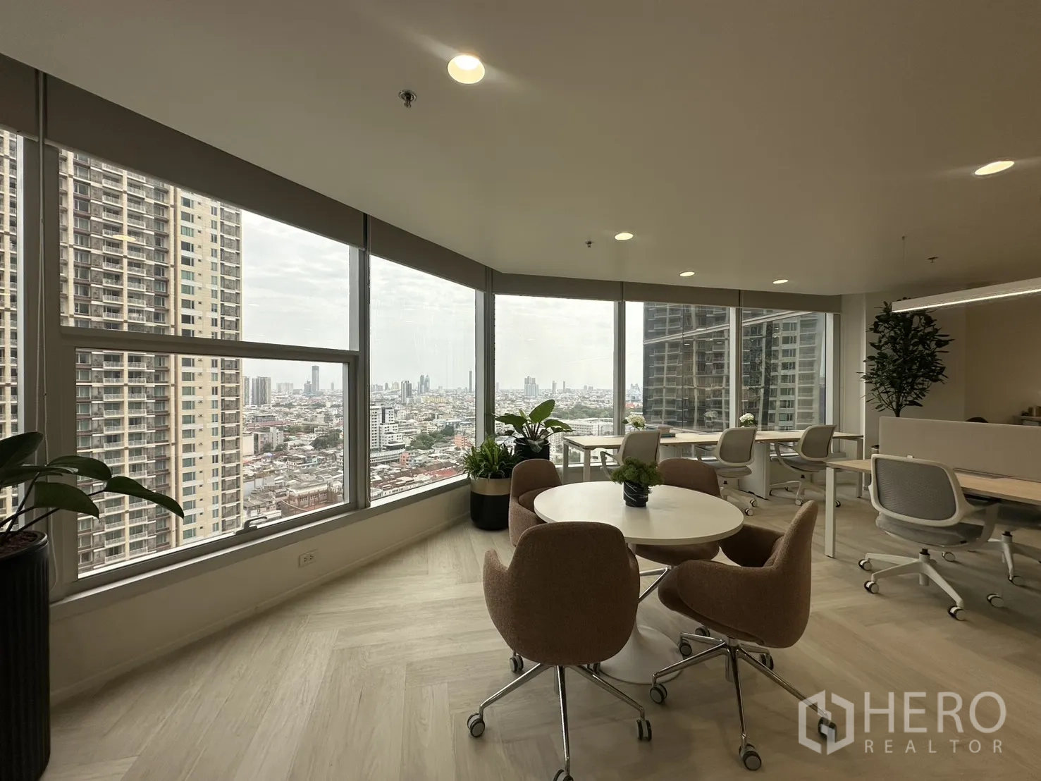 Office Space for rent in Sathon, Bangkok - Corner lounge area with a round table, rolling chairs, and wraparound windows showing skyline views.