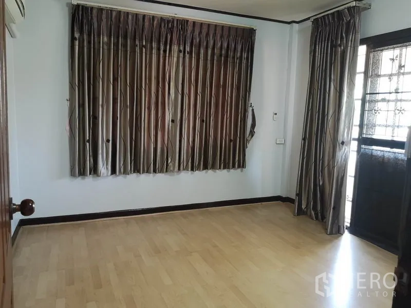 独立式住宅 出售 - 卧室铺木地板，深色窗帘，带阳台门。