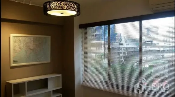 公寓 出租在Khlong Toei, Bangkok - 采光良好的房间，带百叶窗的大窗与城市景观，地图装饰画和置物架。