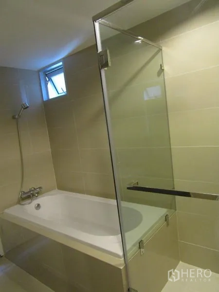 Condominium for sale in Huai Khwang, Bangkok - Bathroom featuring a bathtub with handheld shower and clear glass screen