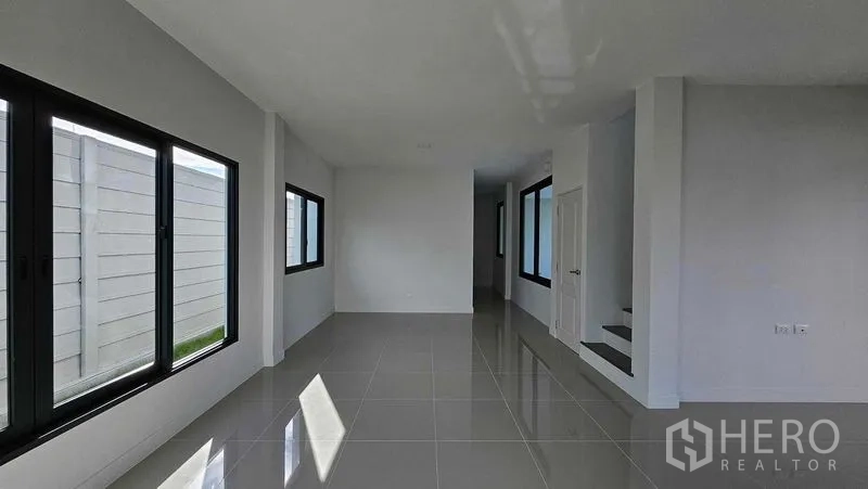 Detached House for sale in Samut Prakan - Bright open-plan room with multiple sliding windows and polished tile floor.