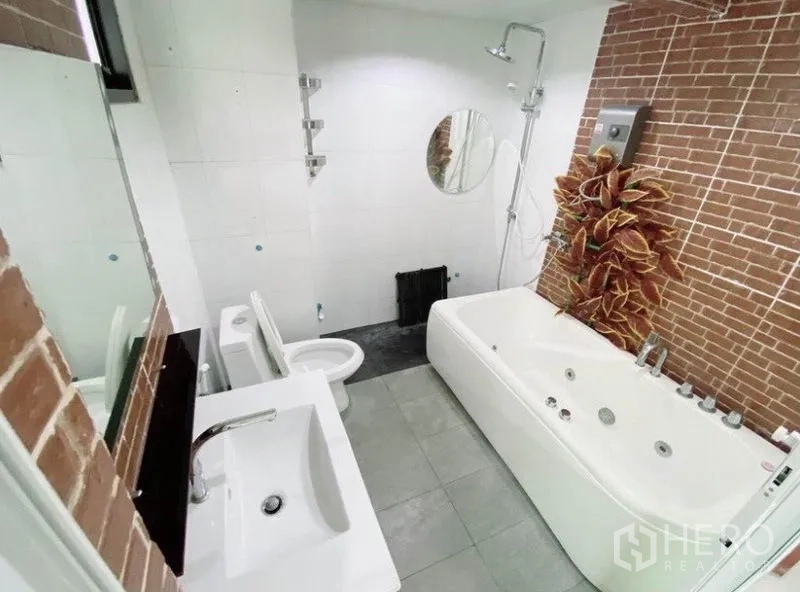 Townhouse for rent in Wang Thonglang, Bangkok - Contemporary bathroom with jacuzzi bathtub, shower, and brick accent wall.