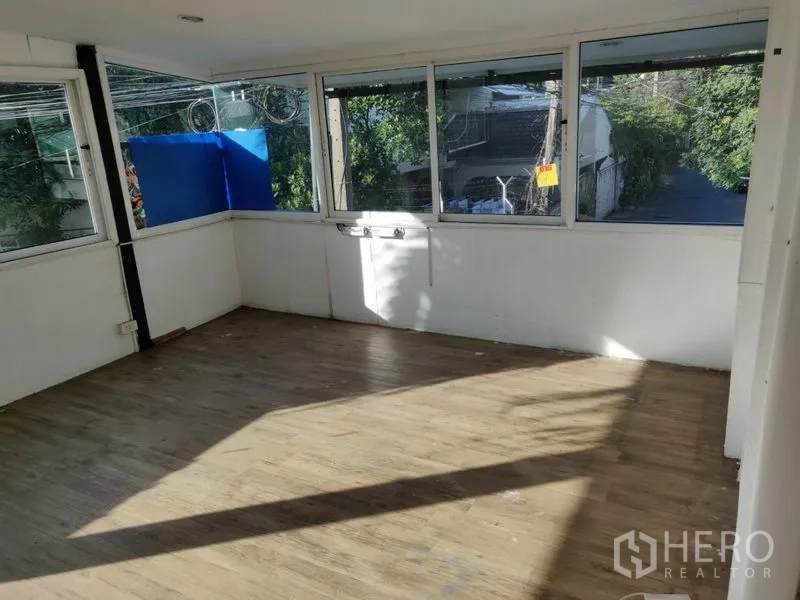 Home Office for rent in Watthana, Bangkok - Upper-floor sunroom with wraparound windows and wood-style flooring.