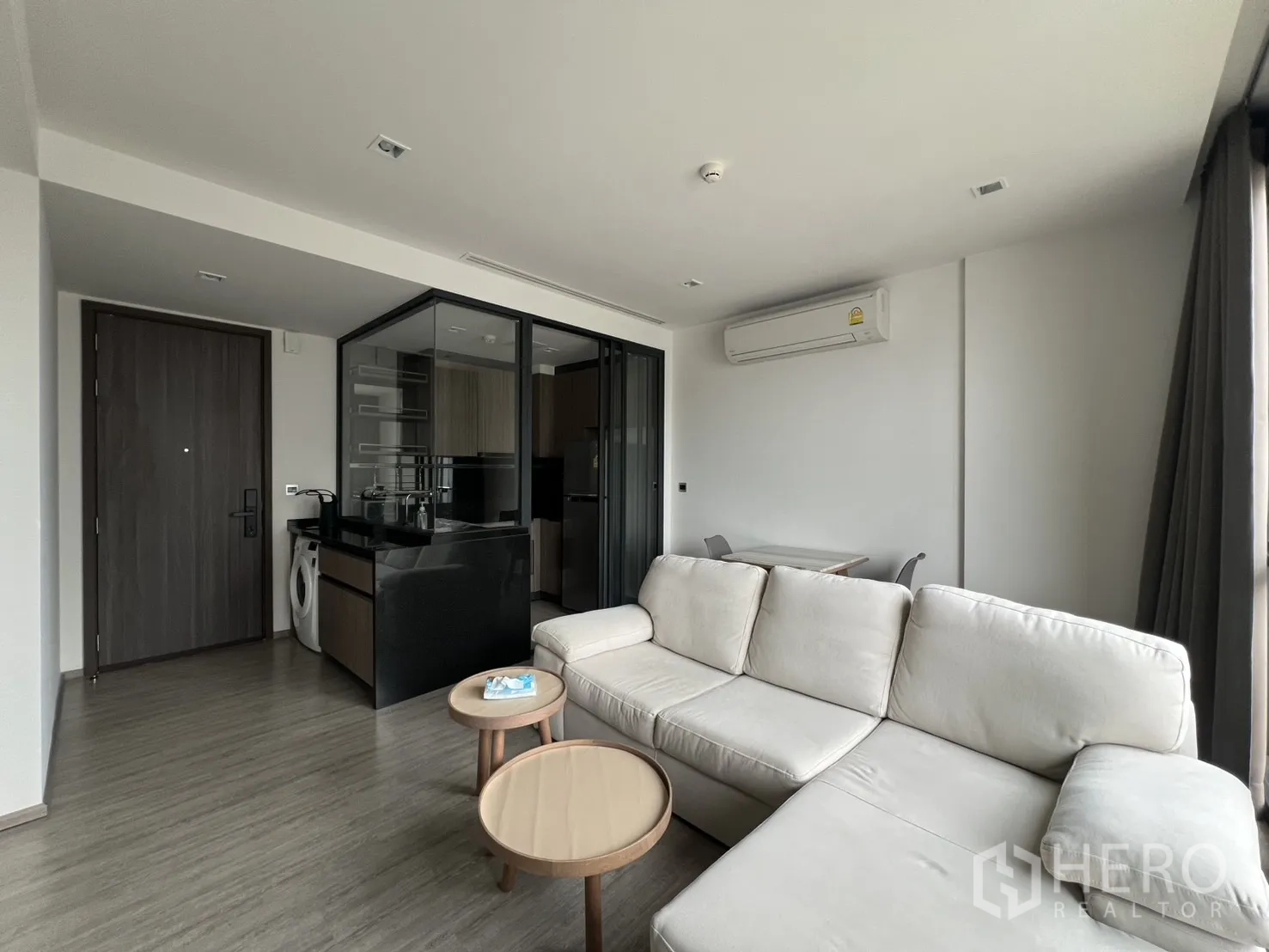 คอนโด for rent in Watthana, Bangkok - พื้นที่นั่งเล่นแบบเปิดโล่งพร้อมโซฟาเข้ามุม โต๊ะกลม เครื่องปรับอากาศ และครัวปิด