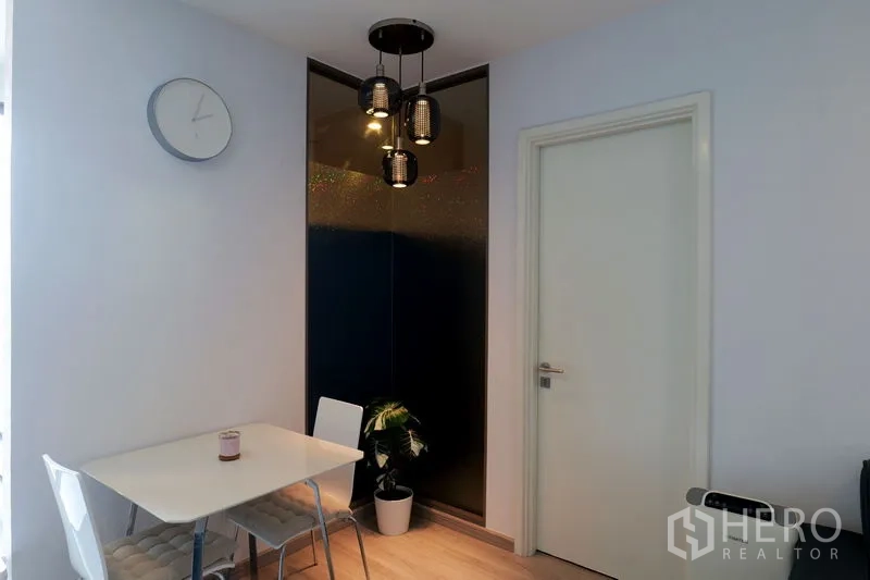 คอนโด ให้เช่าในWatthana, Bangkok - มุมรับประทานอาหารกะทัดรัด เก้าอี้สองตัว นาฬิกาแขวน โคมไฟสไตล์โมเดิร์น และต้นไม้ในกระถาง