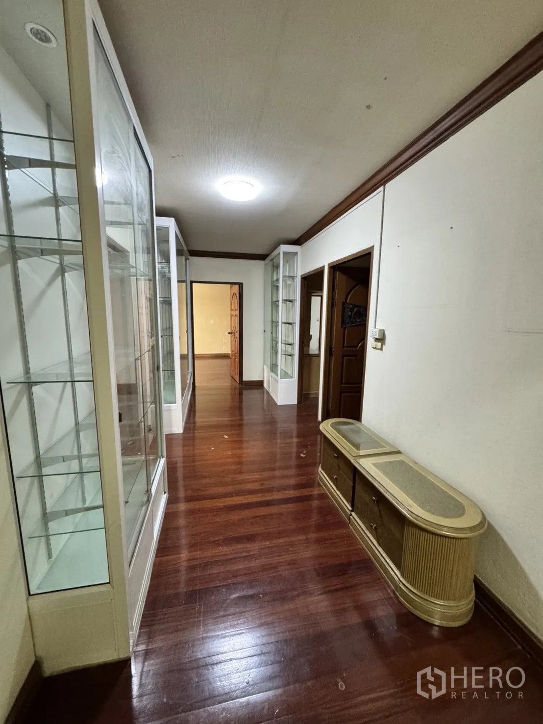 Home Office for rent in Watthana, Bangkok - Corridor fitted with floor-to-ceiling glass display cabinets and wood floors.