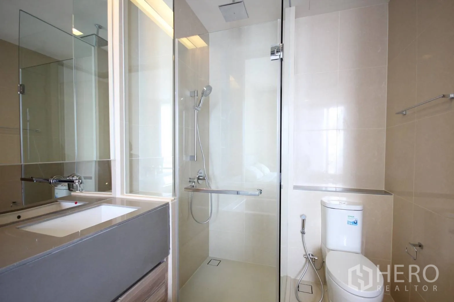 Condominium for rent in Watthana, Bangkok - Contemporary bathroom with glass shower enclosure, vanity and toilet.