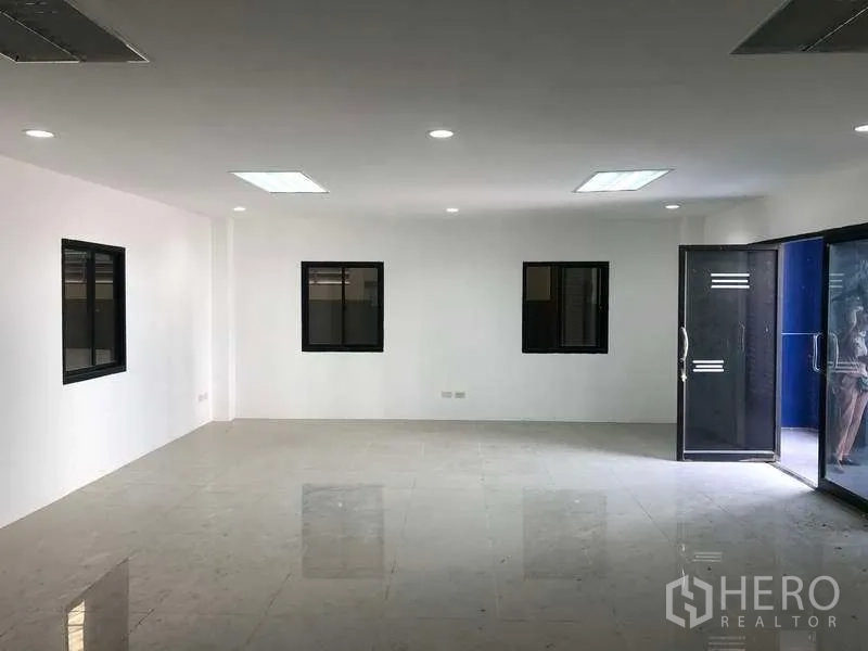 Factory for rent or sale in Samut Prakan - Large open-plan office area with polished tiles and glass entrance doors.