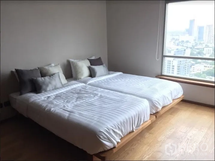 Condominium for rent in Watthana, Bangkok - Second bedroom with twin beds, wood floors and a city-view window.