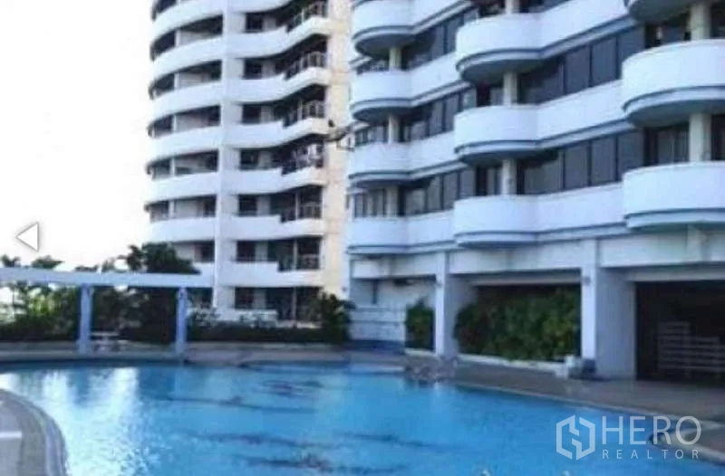 Condominium for sale in Huai Khwang, Bangkok - Condominium pool alongside the building’s curved balconies and landscaped edge.
