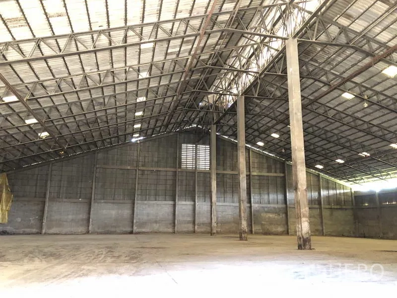 Warehouse for rent in Phra Nakhon Si Ayutthaya - Wide clear-span warehouse showing tall columns, metal roof and bright interior lighting.