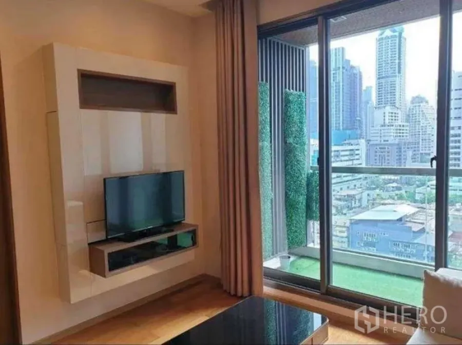 Condominium for rent in Bang Rak, Bangkok - Media wall with TV facing a balcony with artificial turf and expansive city view from a high floor.