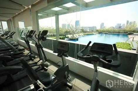 Condominium for rent in Bang Lamung, Chon Buri - Condo fitness center with cardio machines overlooking a large pool and Pattaya skyline.