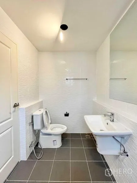 Detached House for rent in Don Mueang, Bangkok - Bright bathroom with white tiles, wall mirror, basin and toilet.