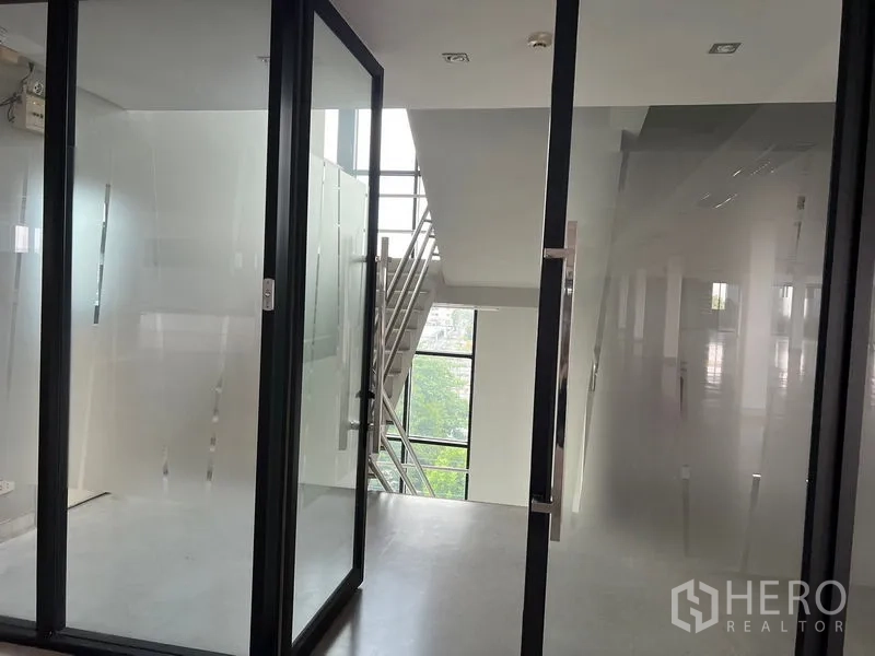 Office Space for rent in Mueang Samut Prakan, Samut Prakan - Glass entry leading to a stairwell corridor with metal handrails and tall window.
