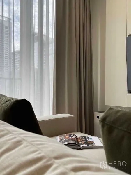 公寓 出售在Watthana, Bangkok - 沙发靠近落地窗，轻纱窗帘与城市天际线景观。