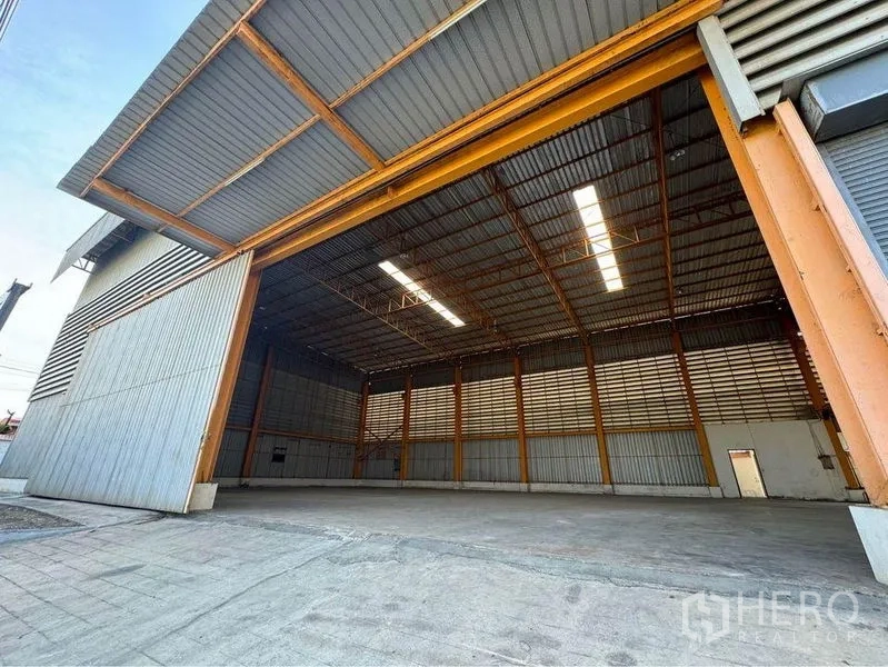 Warehouse for rent or sale in Mueang Samut Sakhon, Samut Sakhon - Open steel sliding doors revealing a high-clear warehouse with skylights and a wide concrete loading apron.