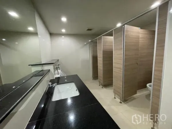 办公空间 出租在Ratchathewi, Bangkok - 现代公共洗手间，黑色石材台面、镜面与多间木纹隔间。