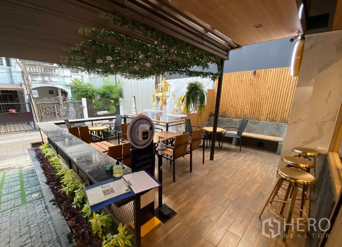 พื้นที่ขายปลีก ให้เช่าในKhlong Toei, Bangkok - ระเบียงกึ่งเอาท์ดอร์ด้านหน้าพร้อมโต๊ะเก้าอี้ ต้นไม้ และพื้นลายไม้ของยูนิตค้าปลีก