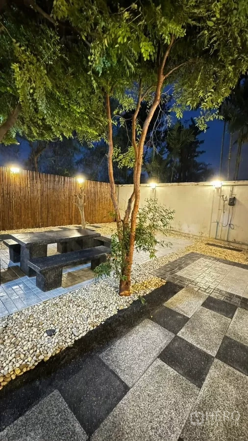 Townhouse for rent or sale in Saphan Sung, Bangkok - Illuminated backyard walkway with patterned paving and bamboo privacy fence.