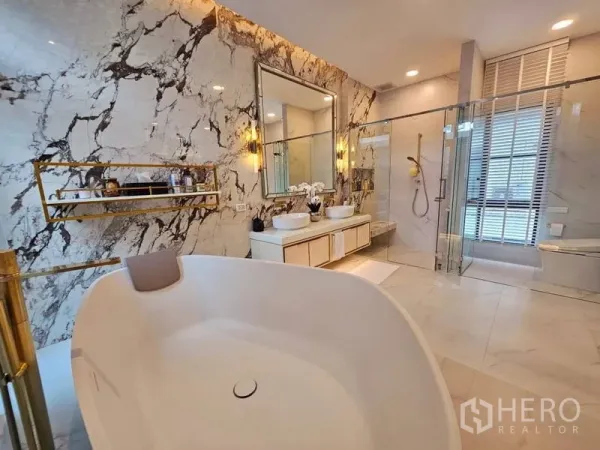 Detached House for rent or sale in Saphan Sung, Bangkok - Luxurious bathroom featuring a freestanding tub, marble accent wall, double vanity and glass shower.