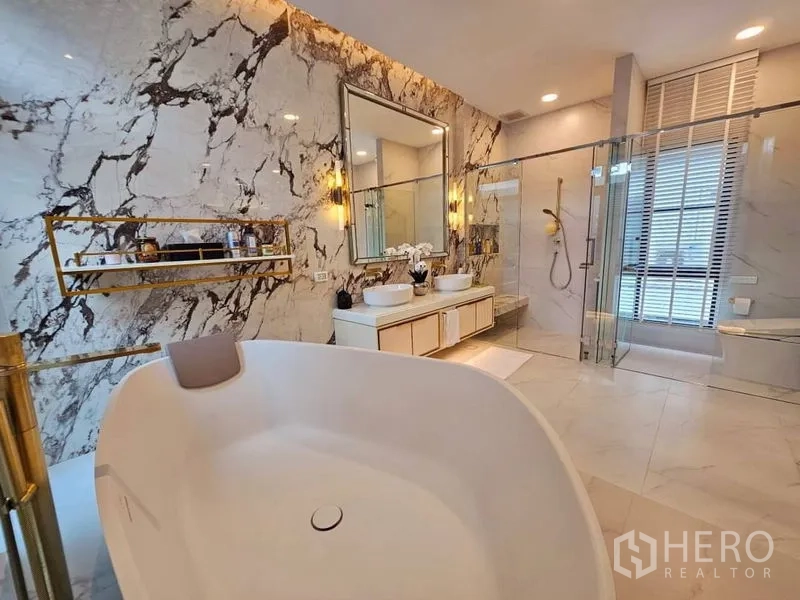 Detached House for rent or sale in Saphan Sung, Bangkok - Luxurious bathroom featuring a freestanding tub, marble accent wall, double vanity and glass shower.