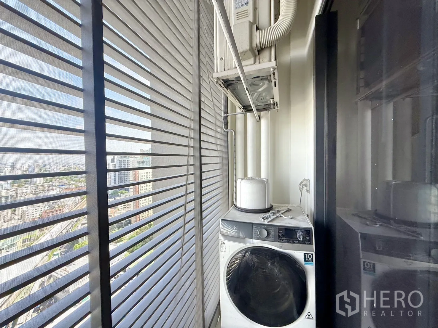 Condominium for sale in Chatuchak, Bangkok - Balcony with washing machine and AC compressor overlooking the city.